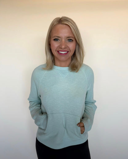 Woman wearing a mint sweater against a plain background
