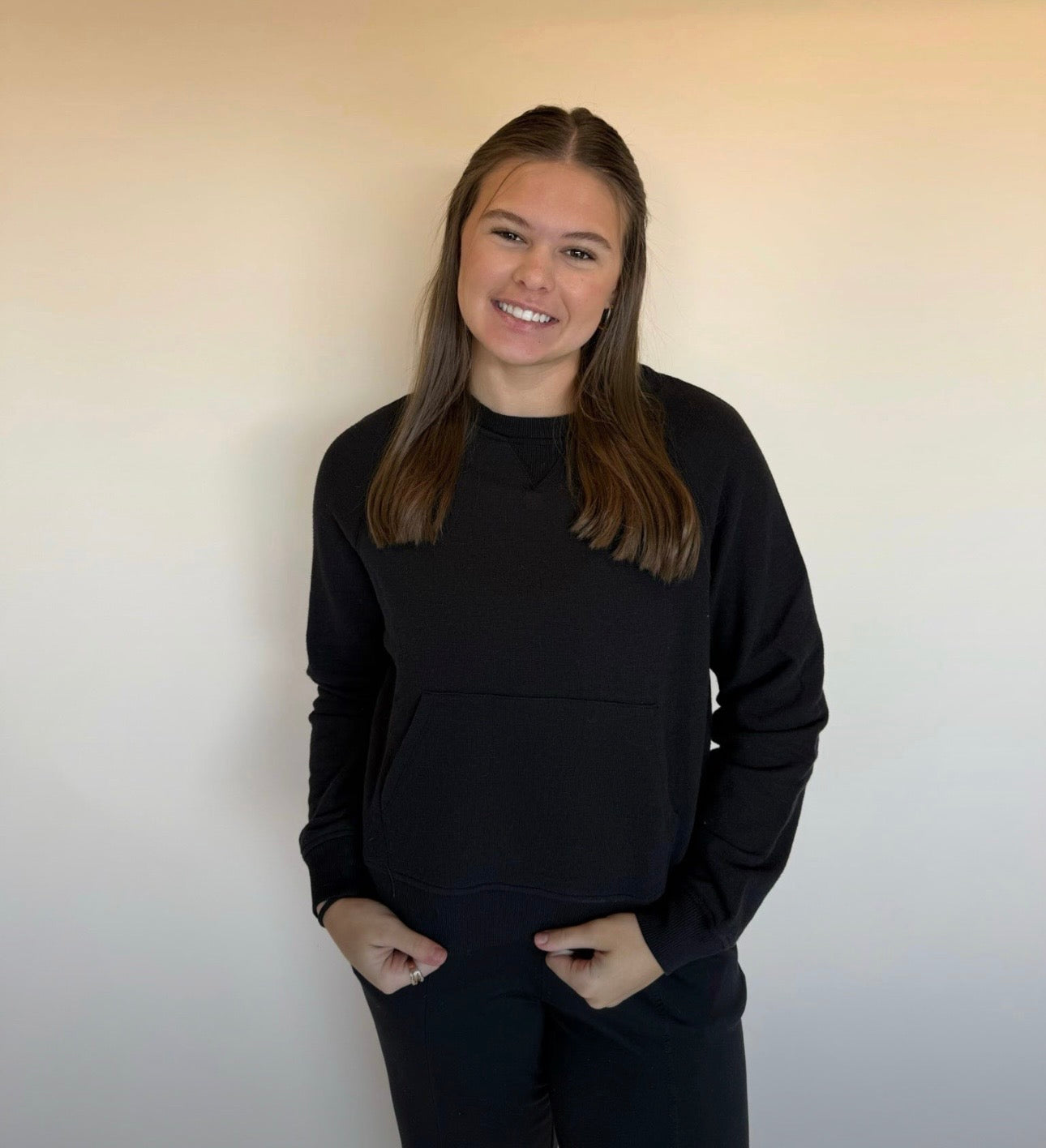 Person wearing a black sweatshirt against a plain background