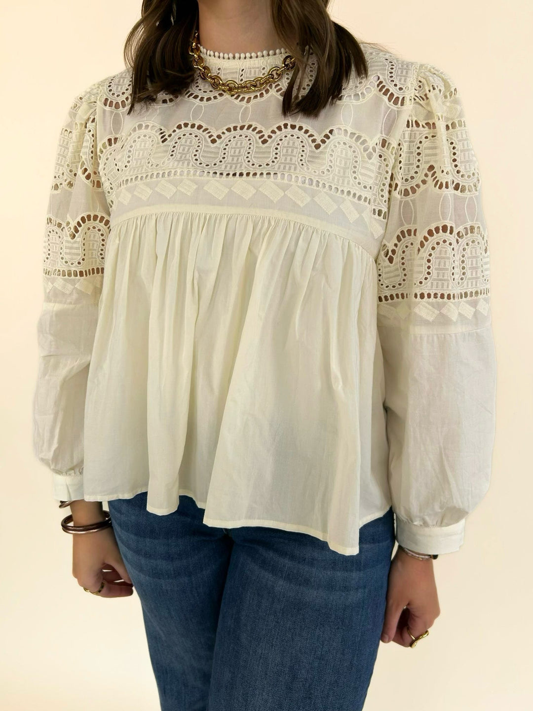 Close-up of the ivory blouse featuring intricate lace yoke detailing, ruffle neckline, and gathered babydoll bodice.