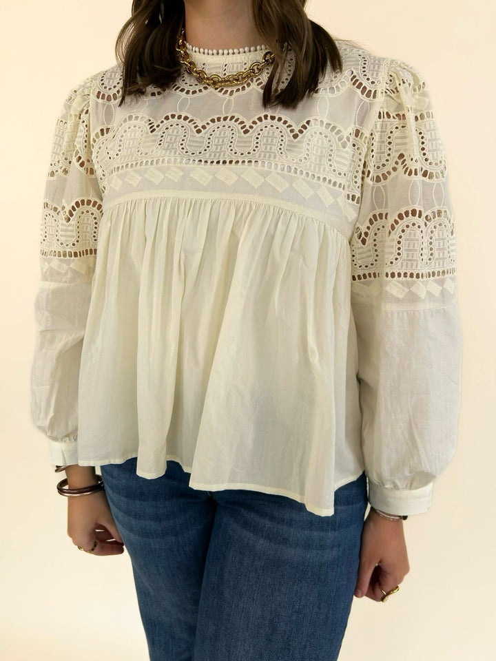 Close-up of the ivory blouse featuring intricate lace yoke detailing, ruffle neckline, and gathered babydoll bodice.