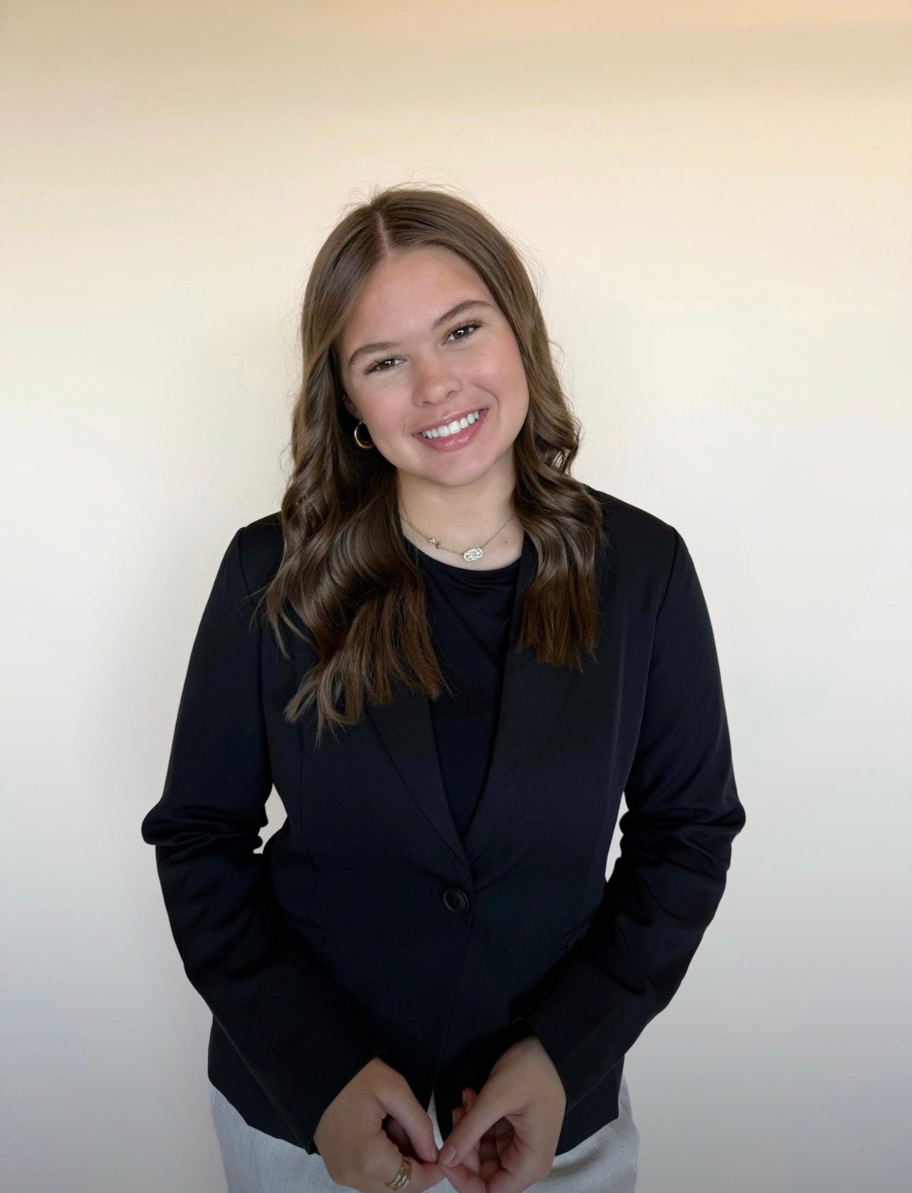 Person wearing a black blazer against a plain background