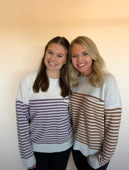 Two women wearing striped sweaters against a plain background