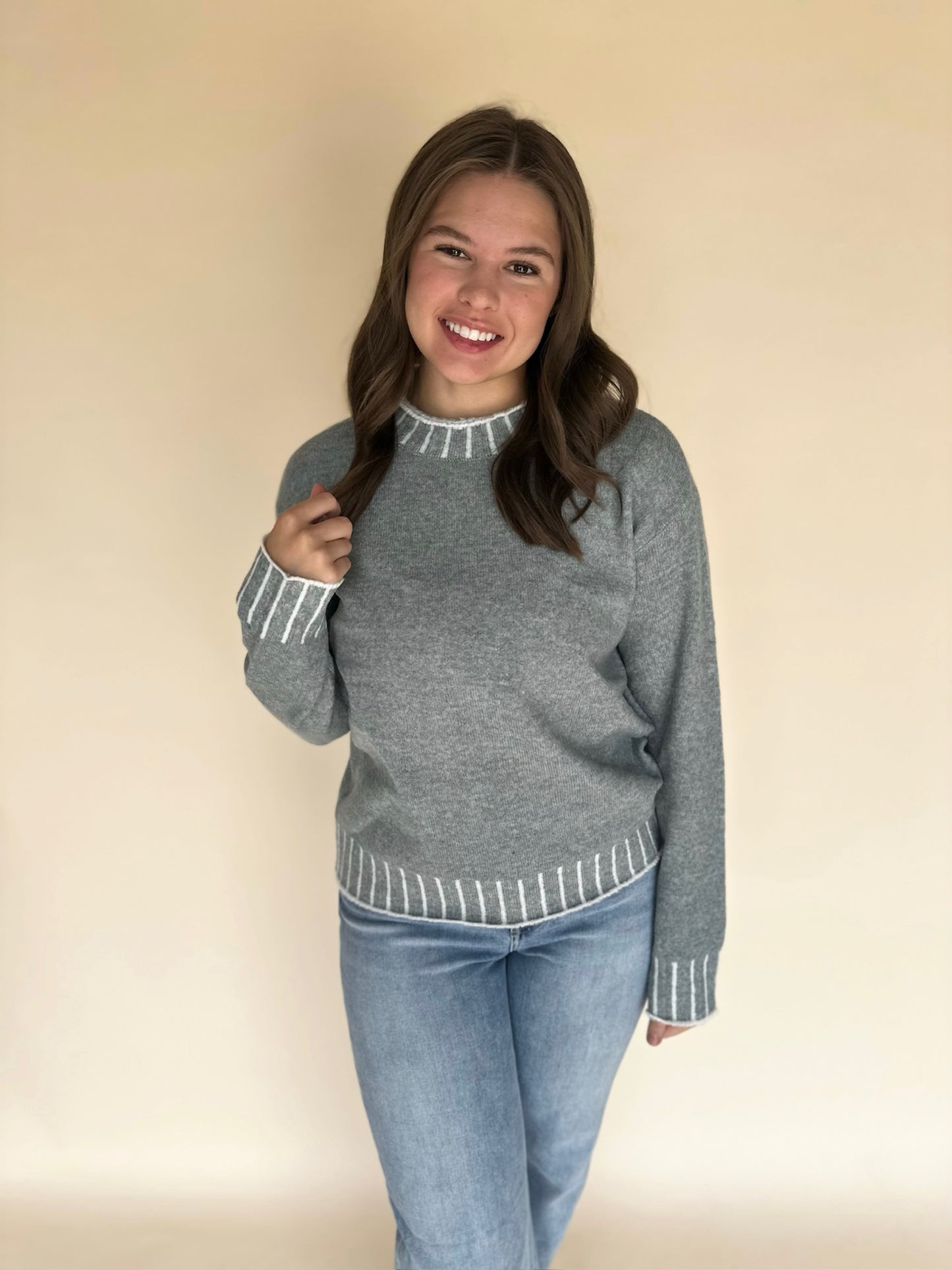 Girl wearing a light blue sweater with white trim against a beige background