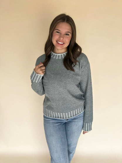 Girl wearing a light blue sweater with white trim against a beige background