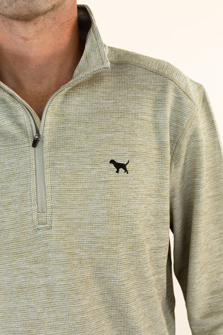 A close-up of a man wearing a textured quarter-zip pullover in a heathered olive color, featuring a small black dog silhouette logo on the left chest.