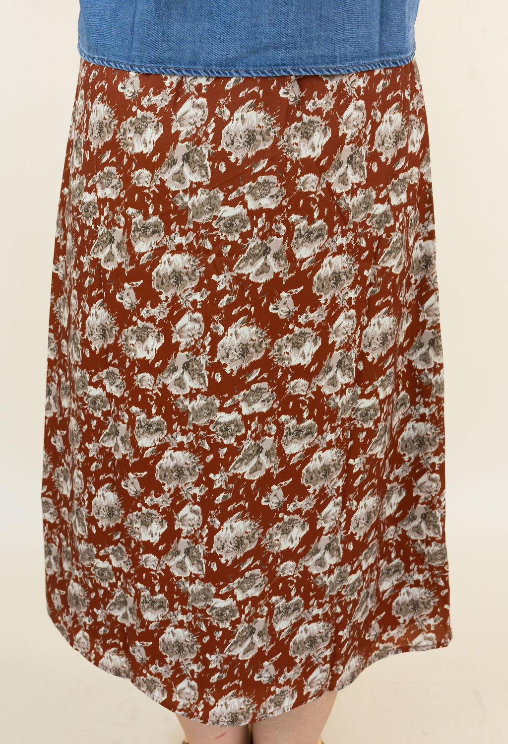 A vintage-style A-line skirt with a hickory base and a gray and white abstract floral pattern, paired with a blue denim waistband, shown on a model against a plain cream background.
