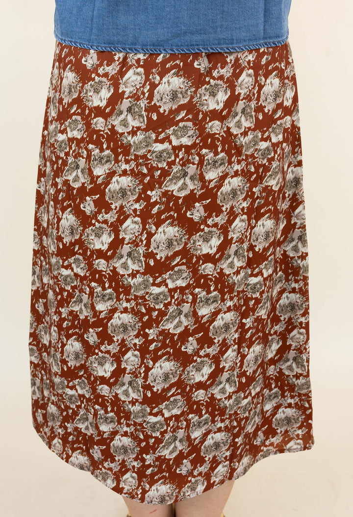 A vintage-style A-line skirt with a hickory base and a gray and white abstract floral pattern, paired with a blue denim waistband, shown on a model against a plain cream background.