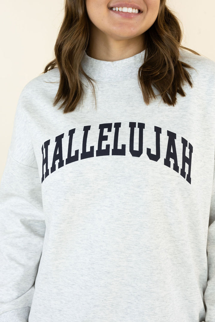A close-up of a person wearing a light heather gray sweatshirt with the word &