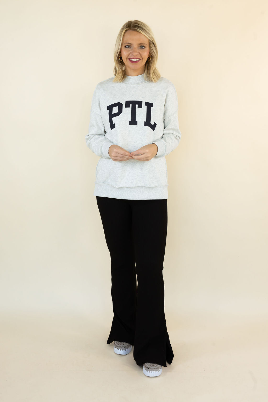 A woman modeling a light gray mock-neck sweatshirt with &