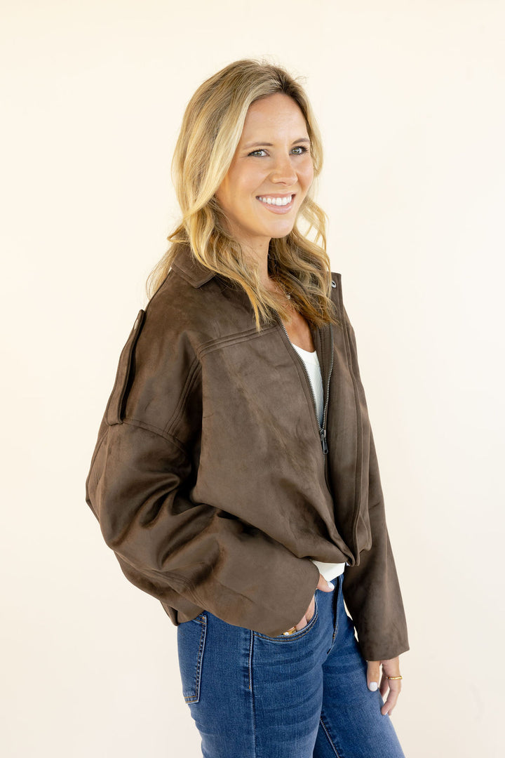Woman modeling dark brown faux suede zip-up jacket showing the relaxed drop shoulder fit, cropped length, and epaulet detailing
