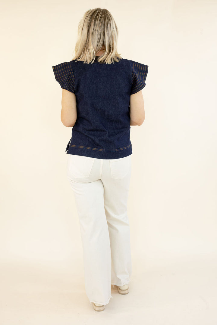 Full back view of THML denim blue short sleeve top showing statement flutter sleeves and relaxed fit styled with white flare jeans