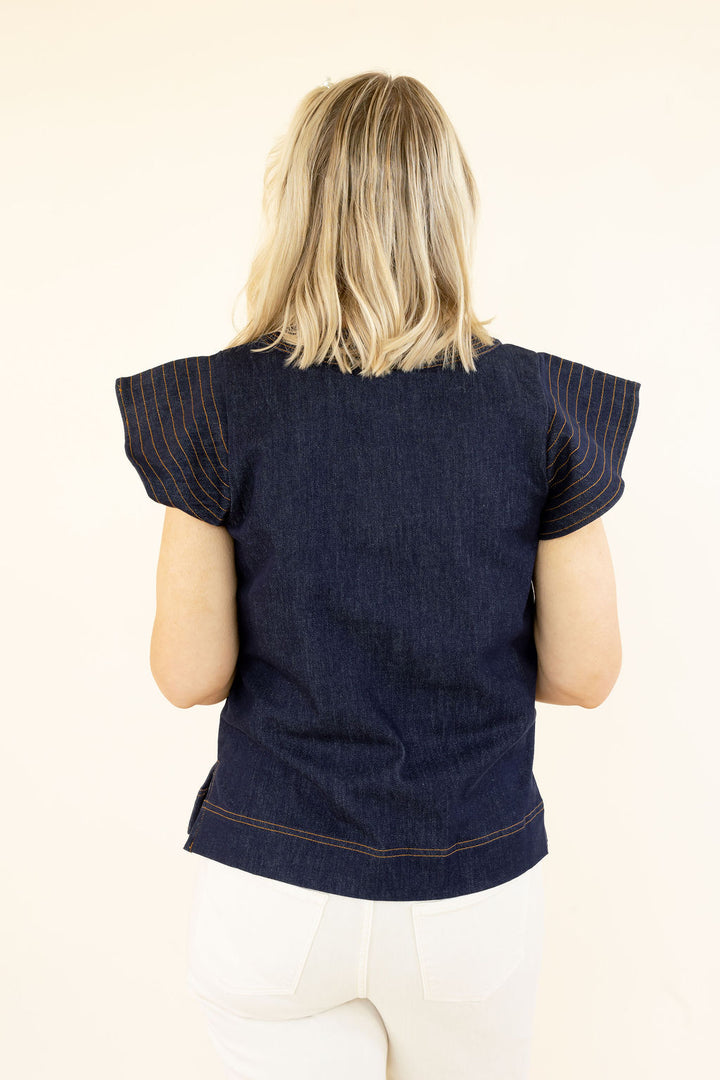 Close back view of THML denim blue top highlighting the layered flutter sleeves, denim fabric, and relaxed silhouette
