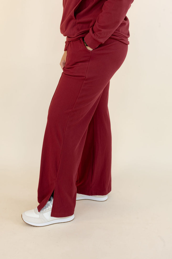 Side view of deep red wide leg lounge pants showing relaxed silhouette, side pocket, and full-length hem