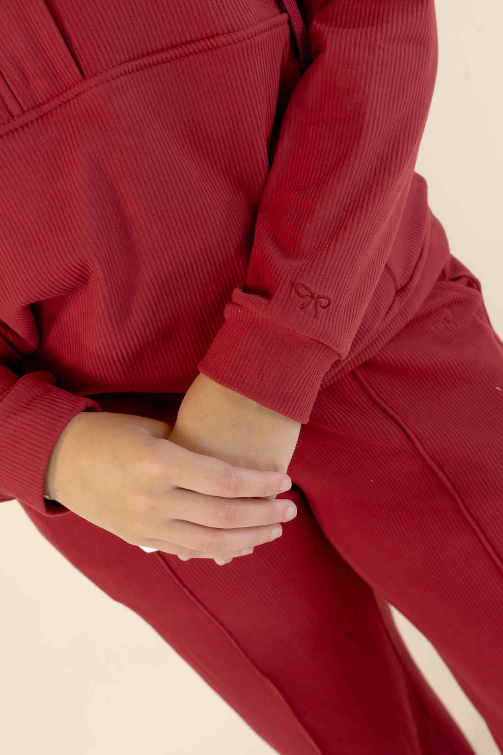 Close-up of deep red lounge set showing textured fabric, long sleeve cuff, and coordinating pants
