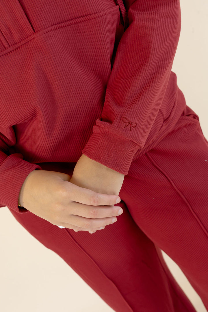 Close-up of deep red lounge set showing textured fabric, long sleeve cuff, and coordinating pants