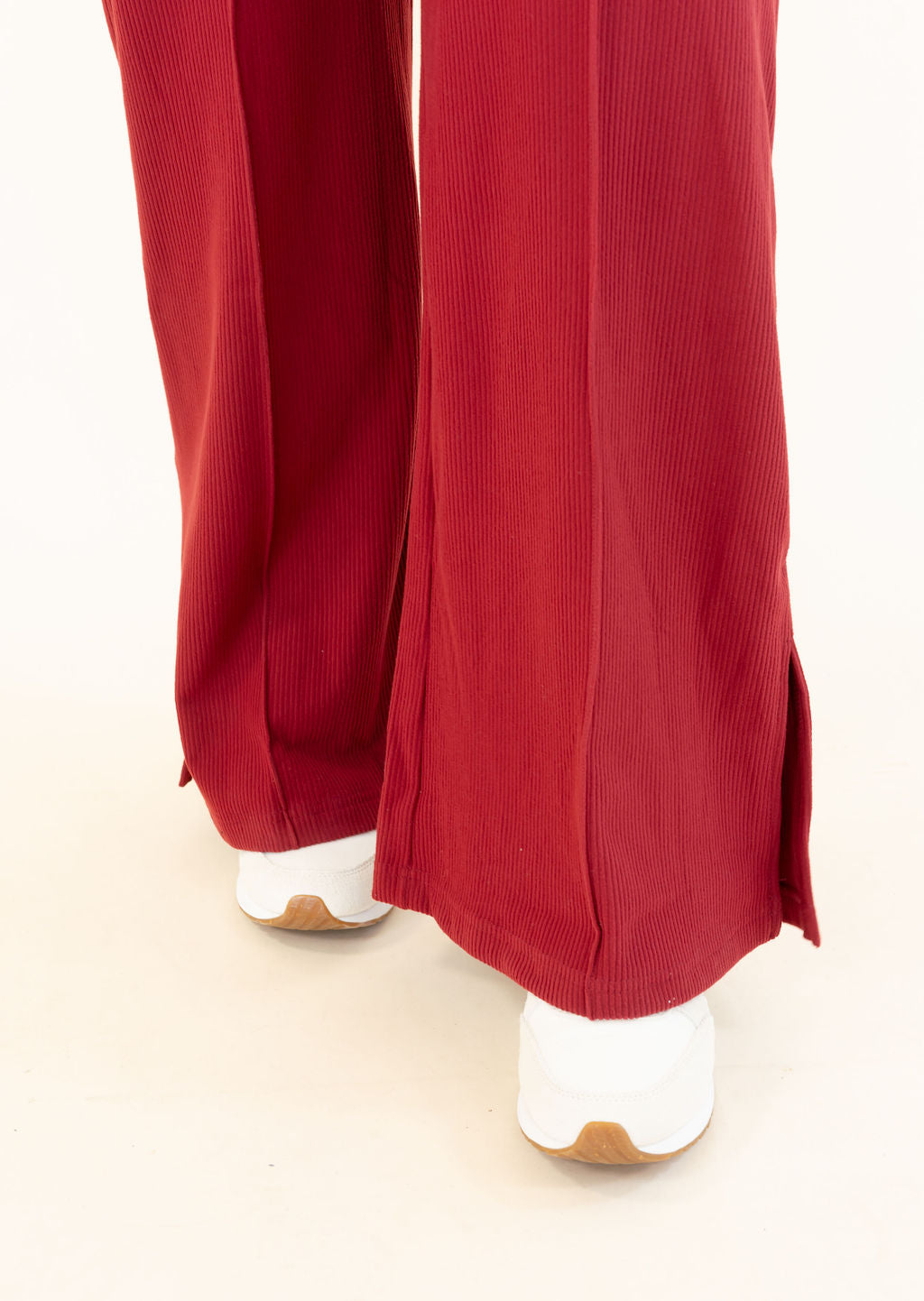 Close-up of deep red wide leg pants showing textured fabric, wide leg silhouette, and side slit hem detail