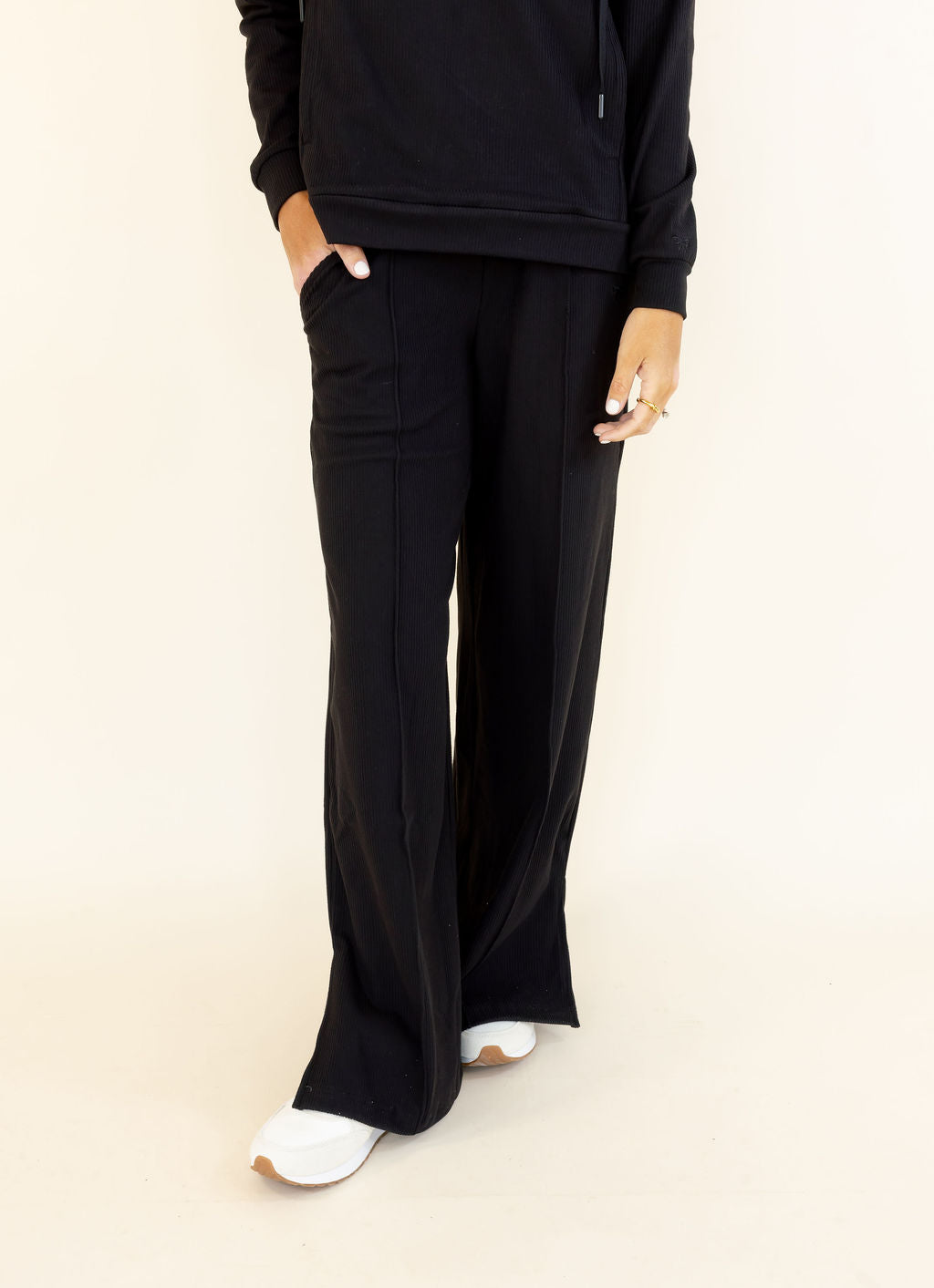 Front view of black wide leg pants featuring a relaxed full-length silhouette and side pockets