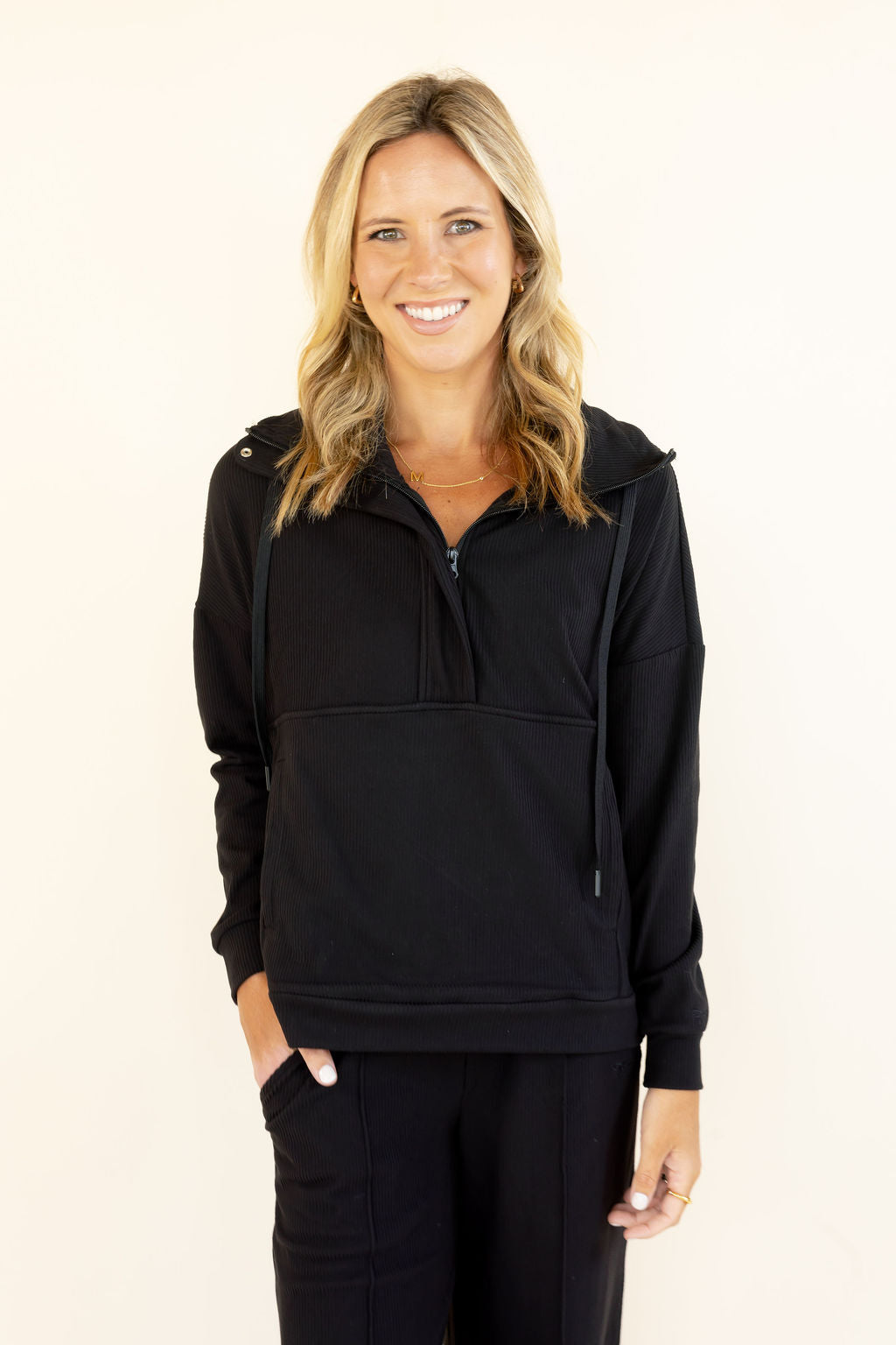 Front view of black hooded half-zip pullover featuring long sleeves, relaxed fit, and drawstring hood
