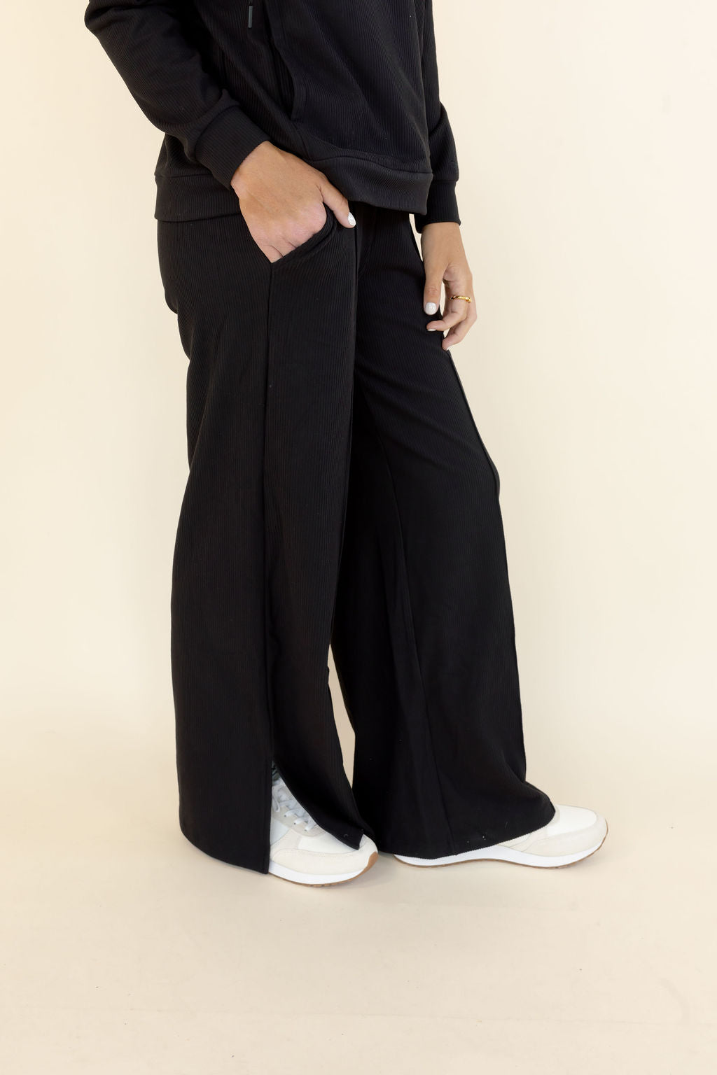 Close-up of black wide leg pants showing relaxed fit, side pocket, and soft draped fabric