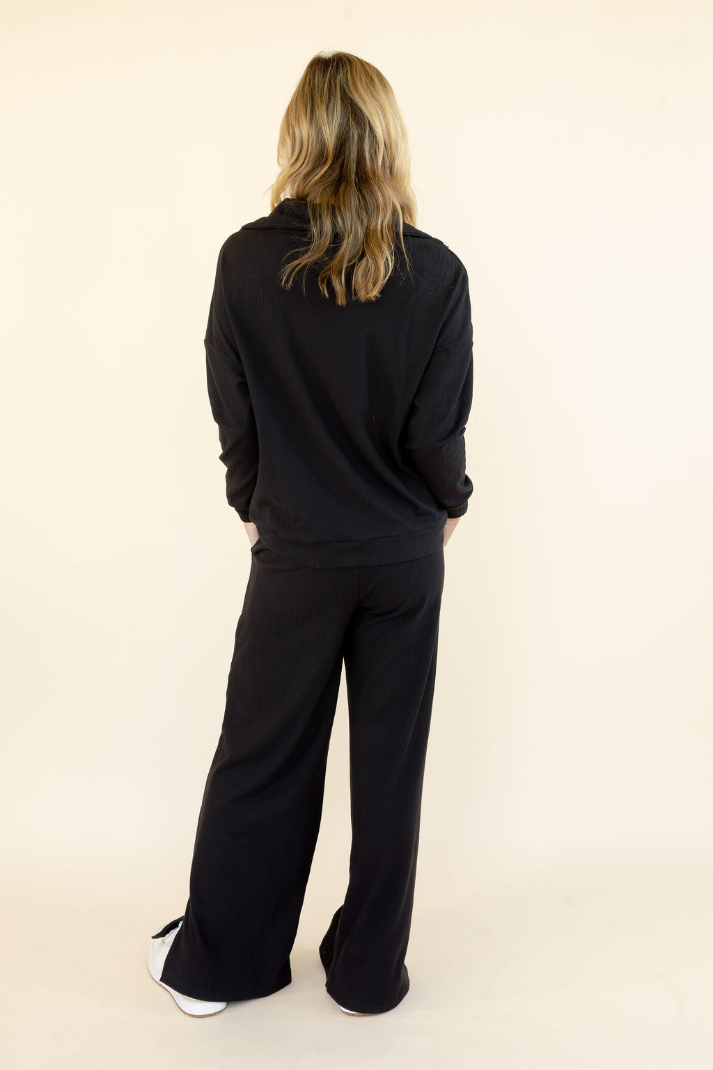 Back view of woman wearing black hooded pullover and matching wide leg pants showing the relaxed silhouette