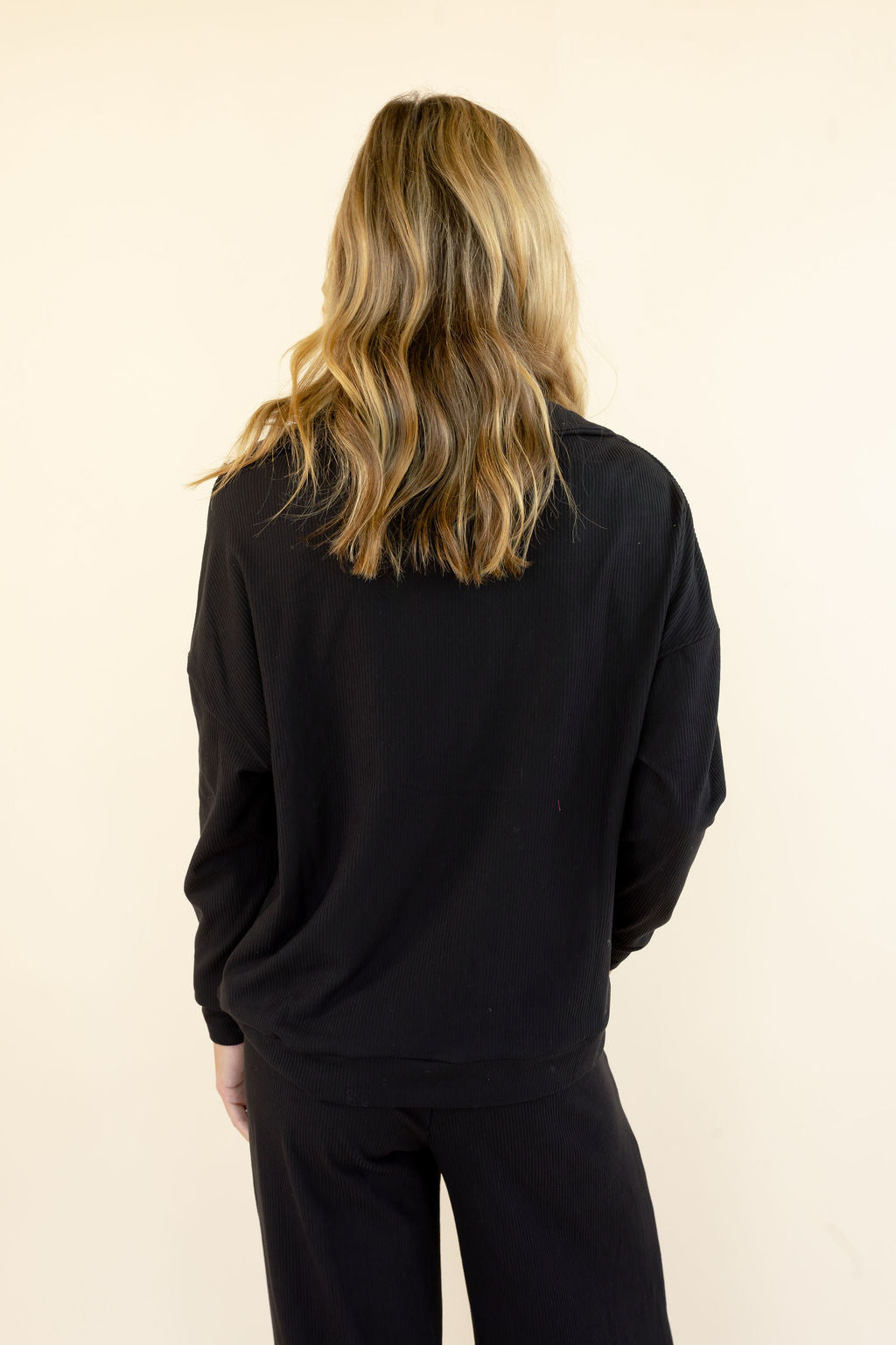Close back view of black hooded pullover showing the hood, long sleeves, and relaxed fit