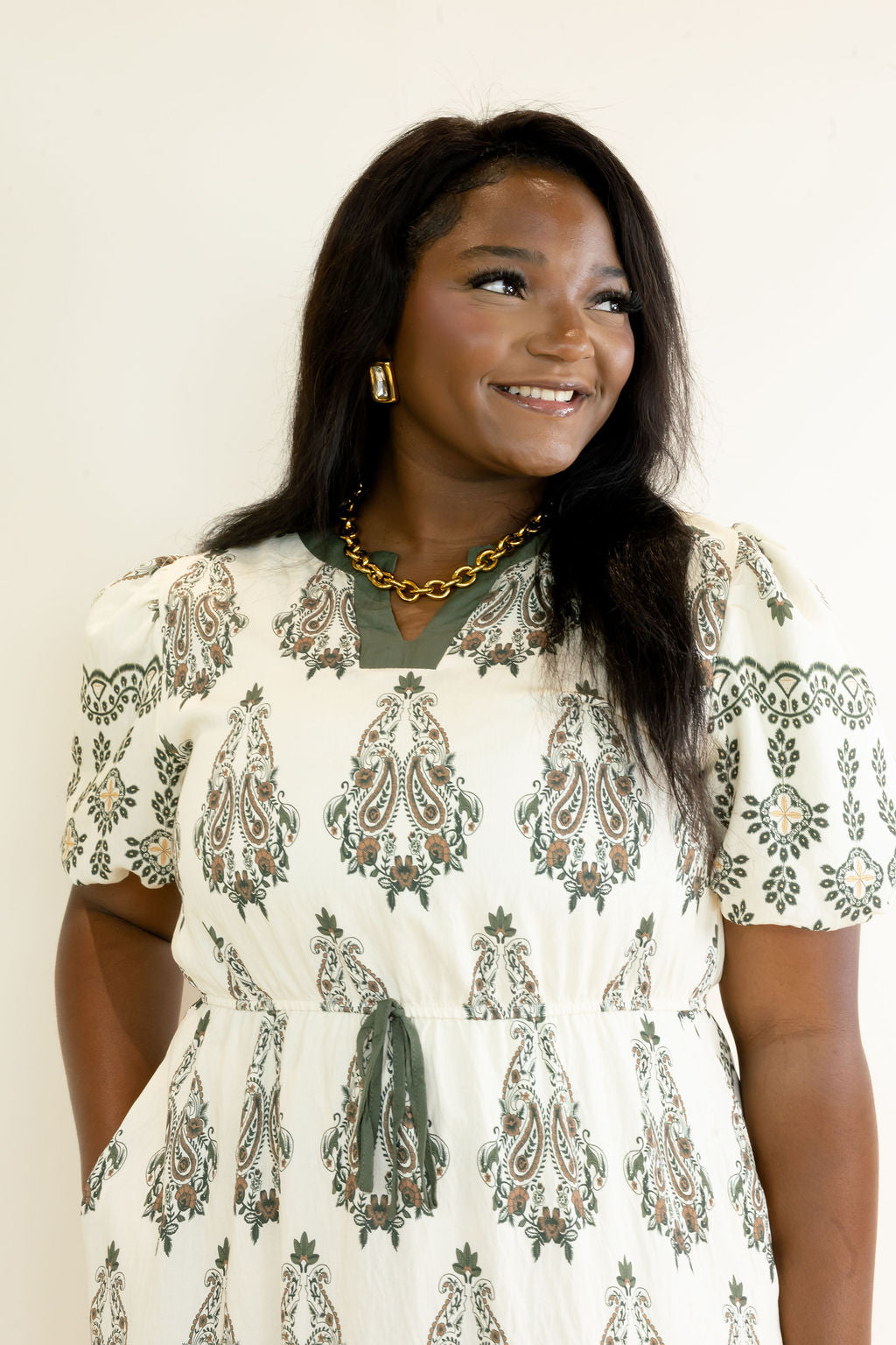 Close-up of ivory and olive green botanical print midi dress highlighting the round neckline, puff short sleeves, and relaxed bodice