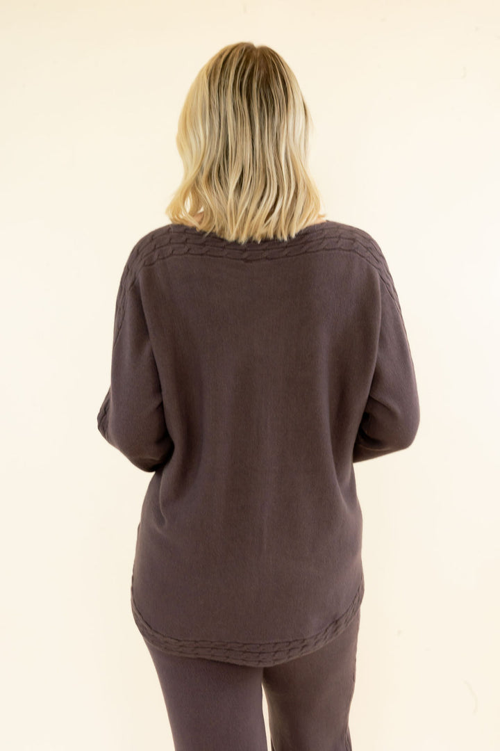 Back view of chocolate brown long sleeve knit pullover highlighting the relaxed fit, textured fabric, and curved hem
