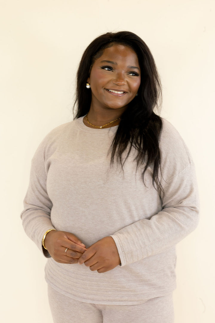 Front view of light taupe knit pullover highlighting the crew neckline, long sleeves, textured fabric, and comfortable relaxed fit