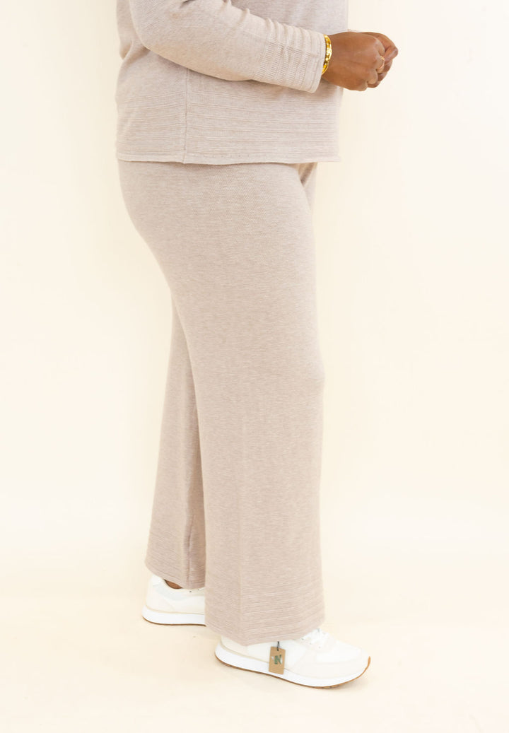 Side view of light taupe knit wide leg pants showing relaxed drape, elastic waistband, and full-length hem