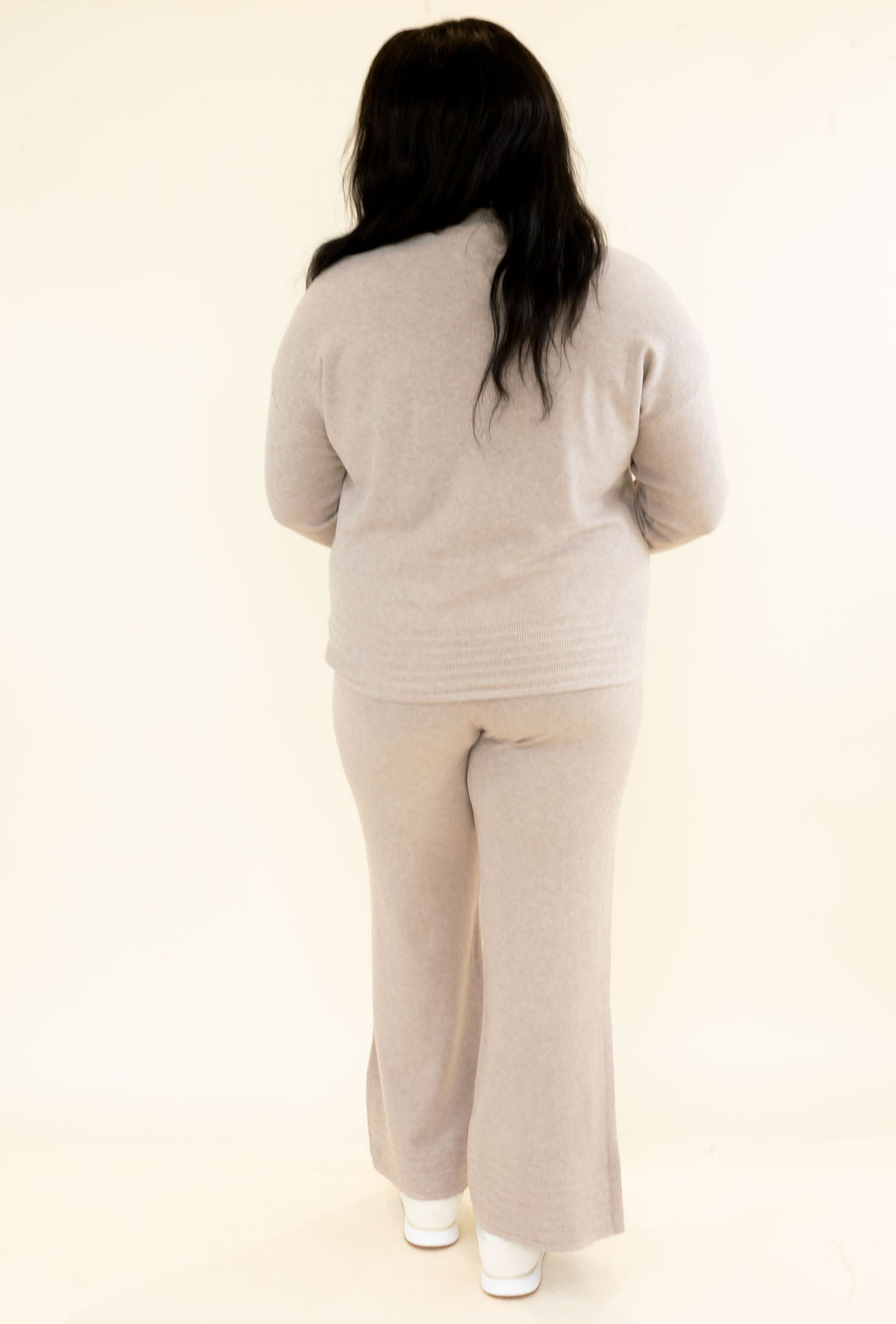 Full back view of woman wearing light taupe matching knit lounge set with long sleeve pullover and wide leg pants