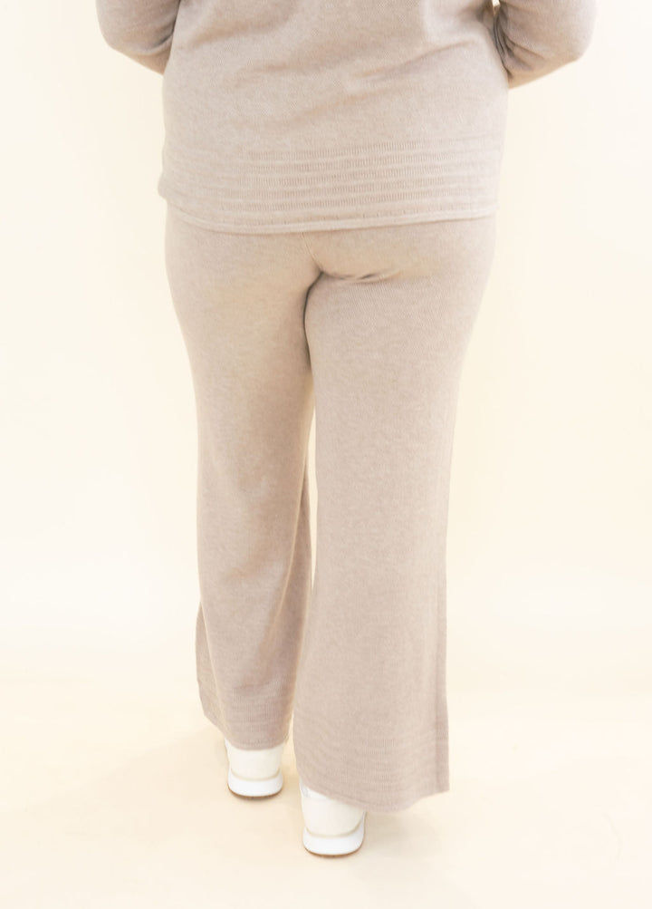 Back view of light taupe knit wide leg pants showing elastic waistband, textured fabric, and relaxed full-length silhouette