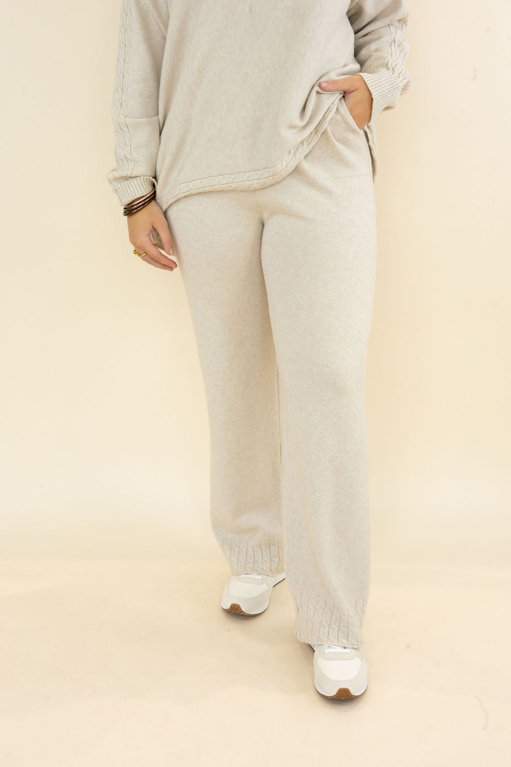 Front view of woman wearing light oatmeal wide leg knit pants with relaxed fit and matching long sleeve pullover top