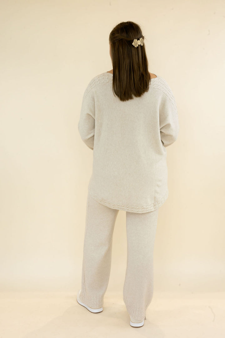 Full back view of woman wearing light oatmeal matching lounge set with relaxed pullover top and wide leg knit pants