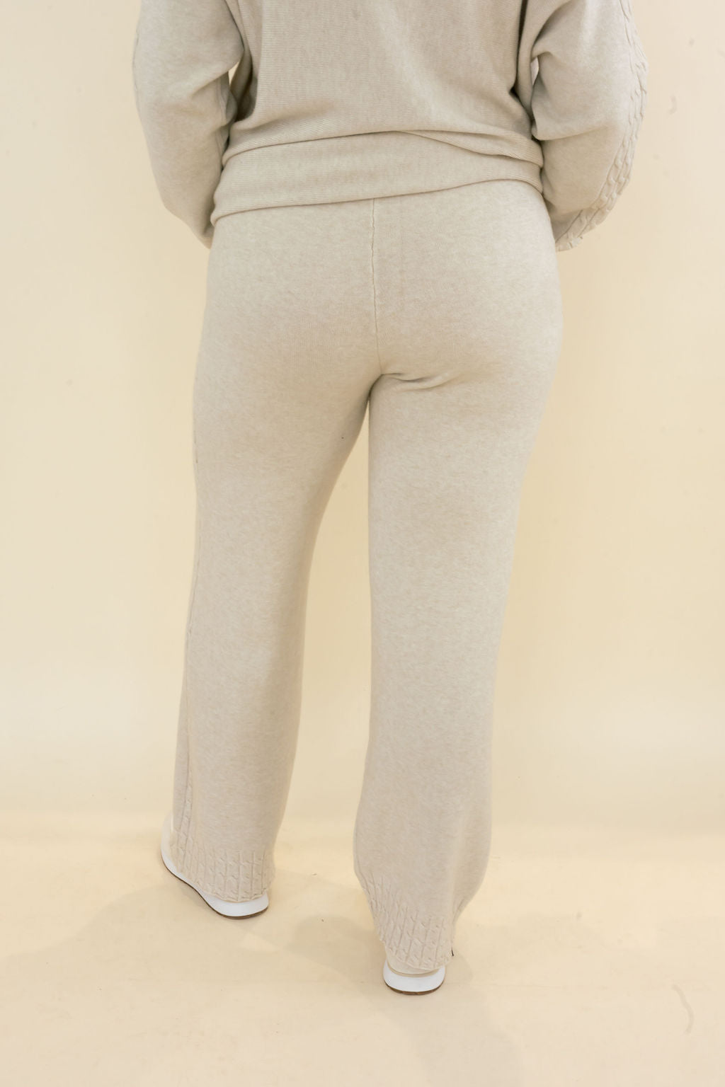 Back view of light oatmeal knit wide leg pants showing elastic waist, relaxed fit, and full-length silhouette