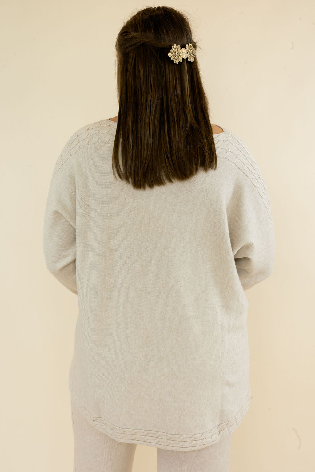  Back view of light oatmeal textured knit pullover showing relaxed oversized fit, rounded high-low hem, and long sleeves