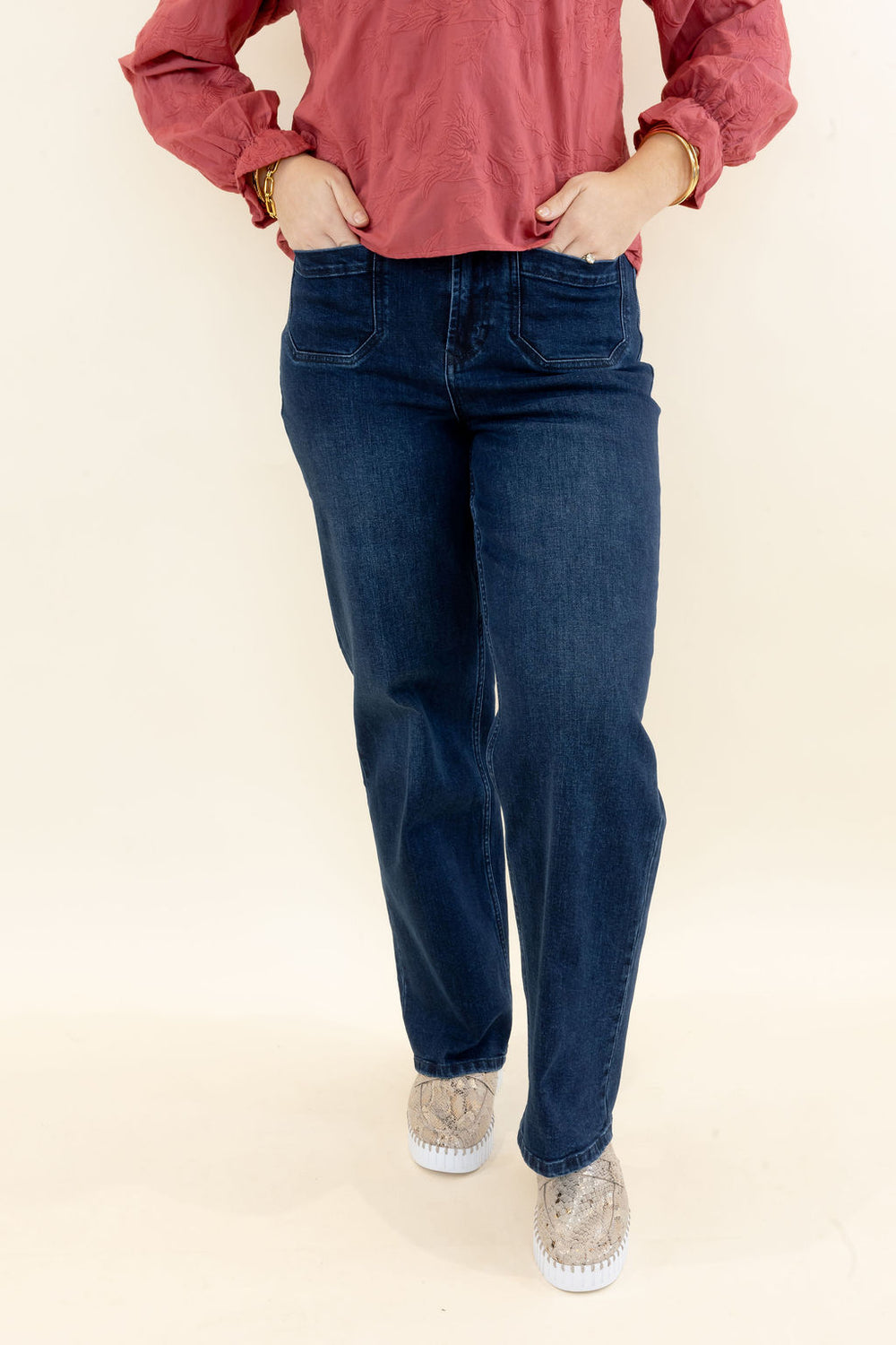 Front view of woman wearing dark wash wide leg jeans with high-rise waist, front pockets, and relaxed leg styled with a rust blouse