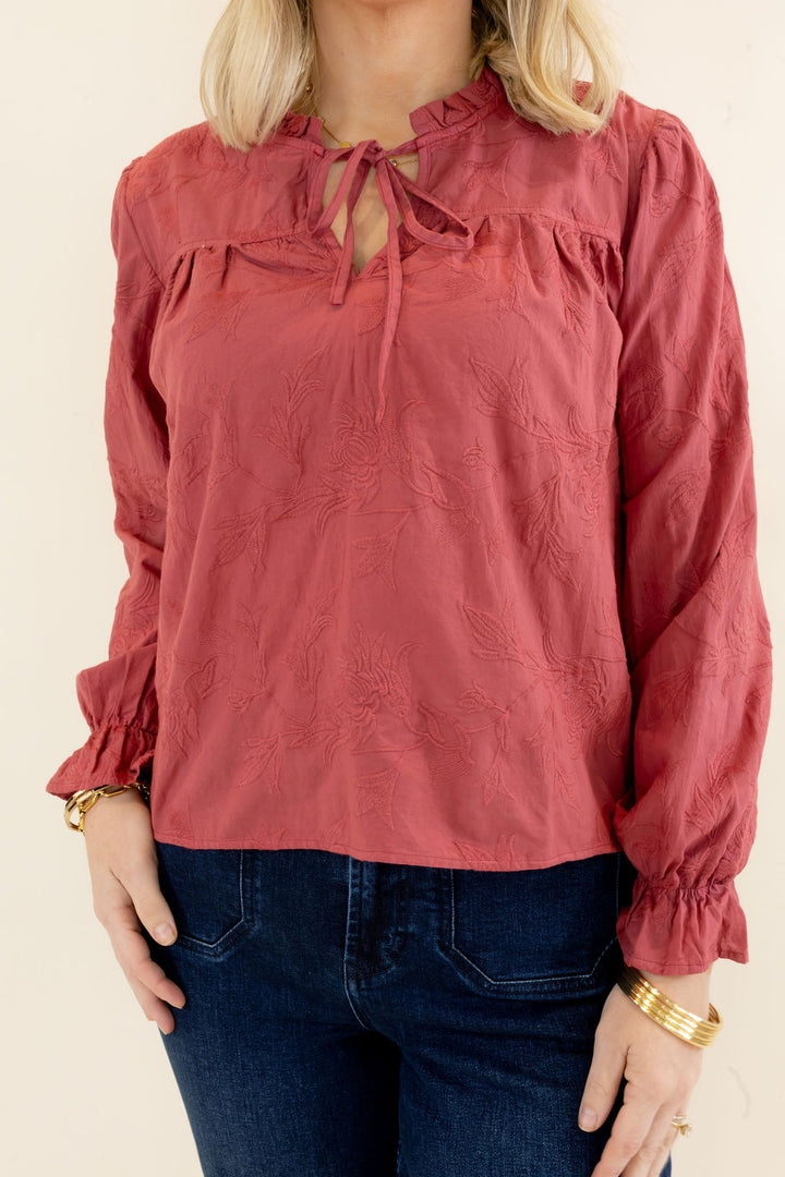 Front view of rust red blouse featuring ruffled neckline, tie-front detail, gathered yoke, and long balloon sleeves