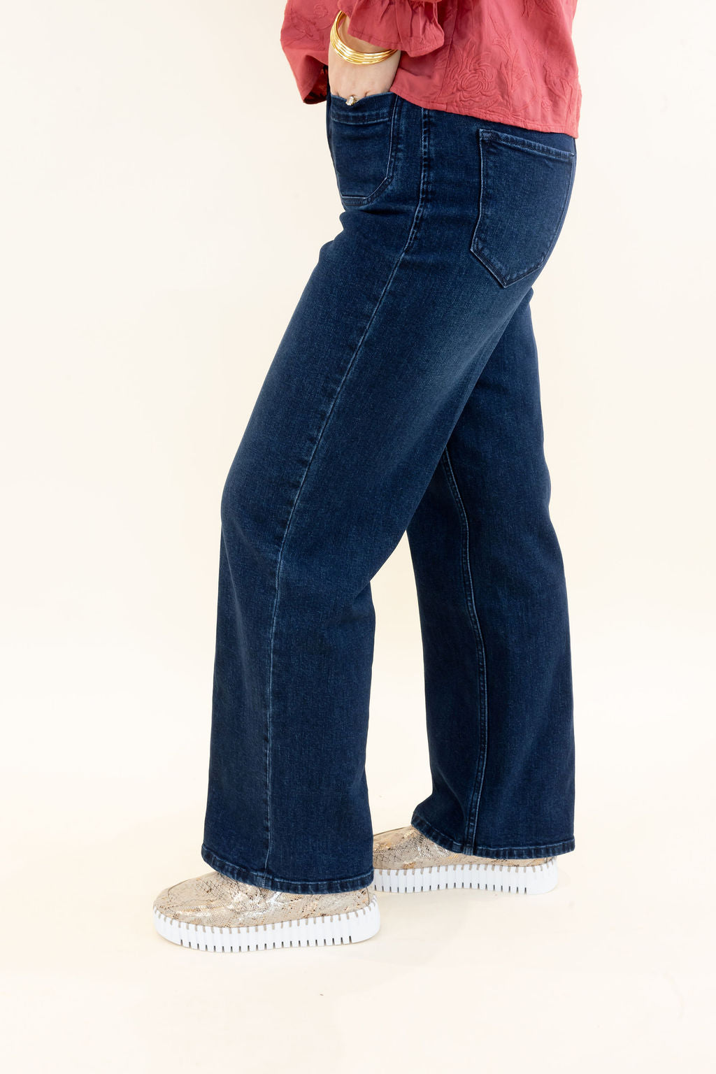 Side view of dark wash wide leg jeans featuring a high-rise fit, five-pocket design, subtle fading, and full-length hem
