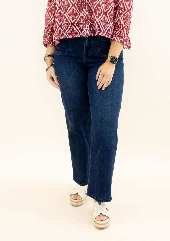 Front view of woman modeling dark wash wide leg jeans with high-rise waist and relaxed silhouette styled with a red printed blouse