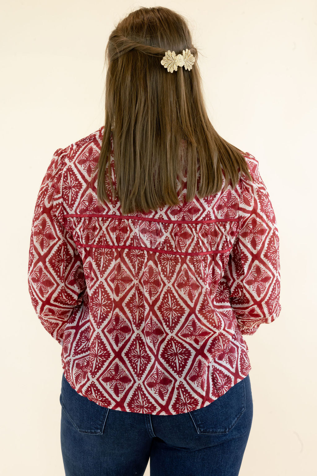 Back view of red and ivory geometric print blouse highlighting the allover pattern, relaxed fit, and three-quarter sleeves
