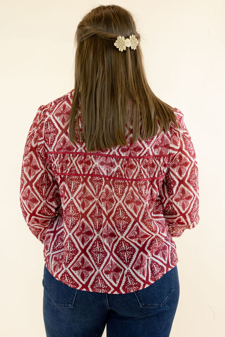 Back view of red and ivory geometric print blouse highlighting the allover pattern, relaxed fit, and three-quarter sleeves