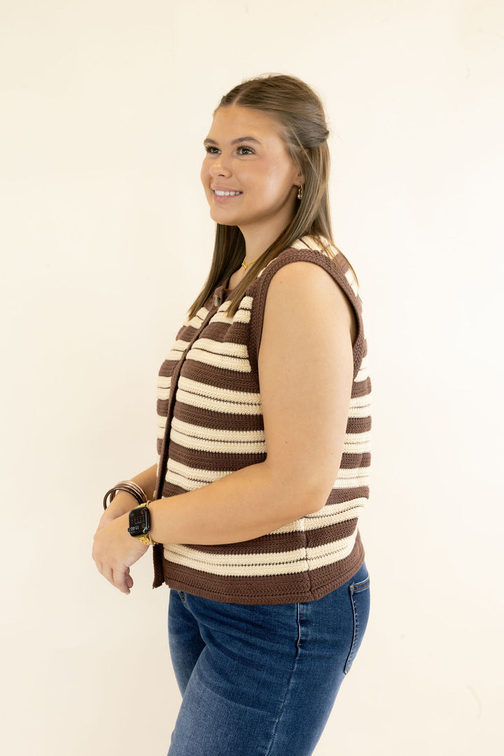 Three-quarter view of brown and cream striped knit sweater vest showing sleeveless silhouette, button-front design, and contrast trim