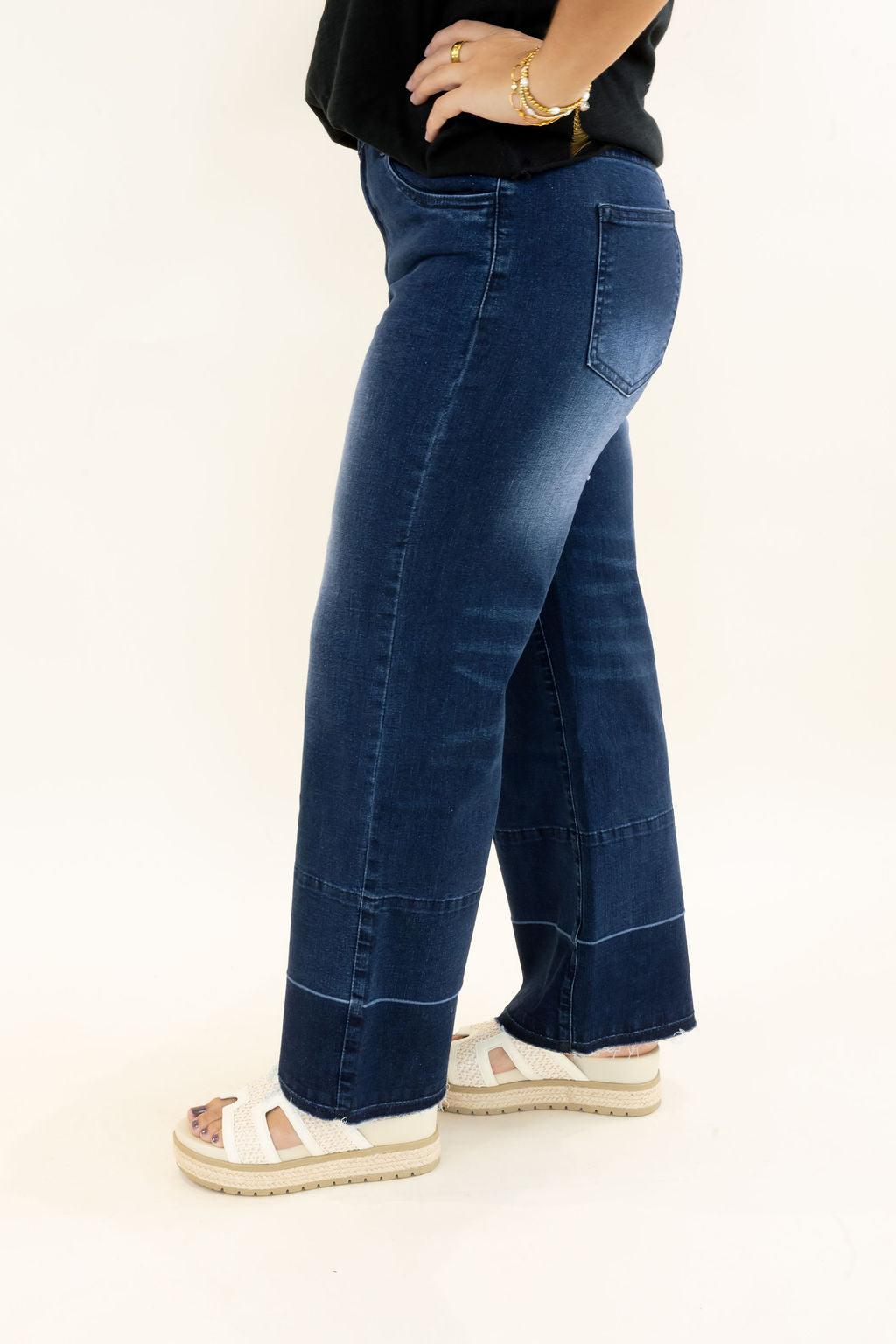 Side view of EverStretch indigo dark denim cropped wide leg jeans featuring faded wash, release hem seam detail, and raw hem
