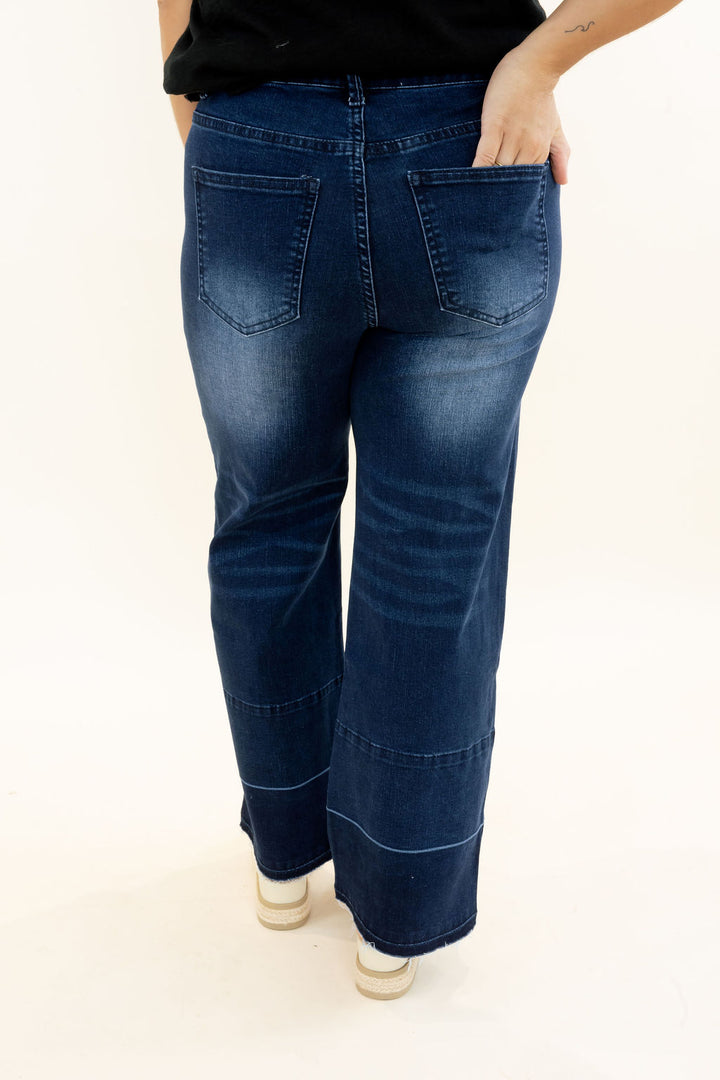 Back view of EverStretch indigo dark denim wide crop jeans showing back pockets, faded wash, wide legs, seam detailing, and raw release hem
