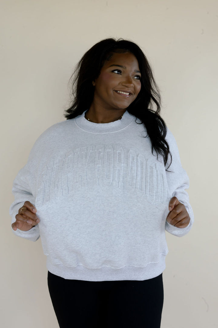 Woman modeling heather gray Simply For Good crewneck sweatshirt with tonal raised lettering, long sleeves, and relaxed fit