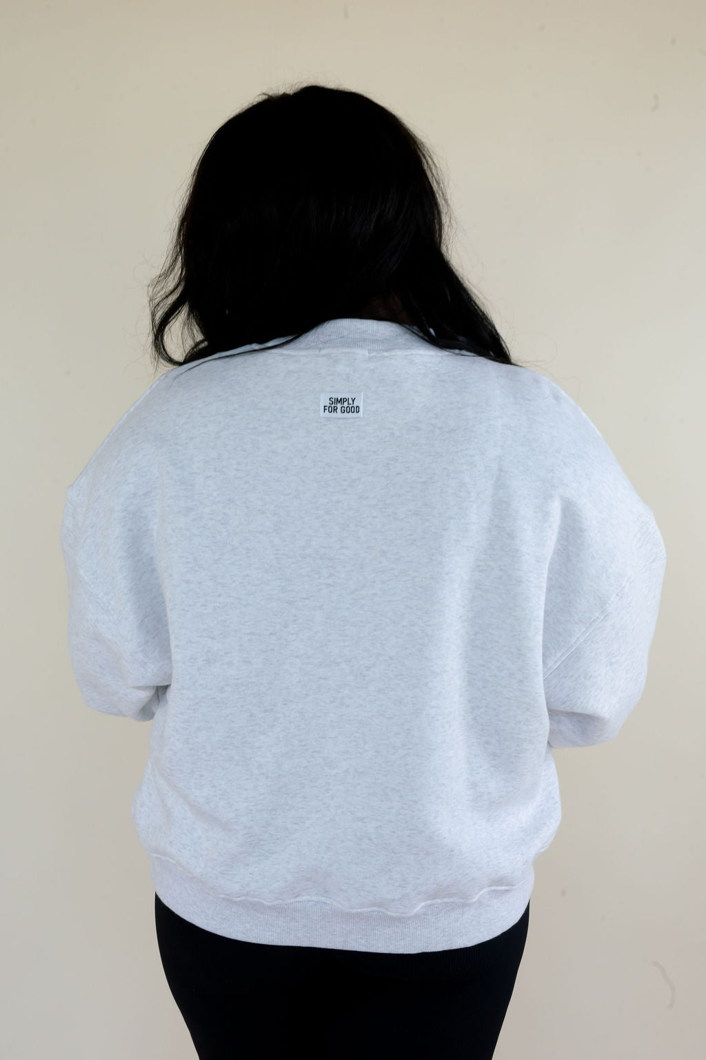 Back view of heather gray Simply For Good crewneck sweatshirt showing relaxed silhouette and small Simply For Good back neck detail