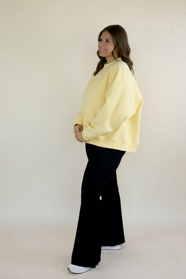 Side view of butter yellow Simply For Good crewneck sweatshirt showing relaxed fit, long sleeves, and ribbed hem