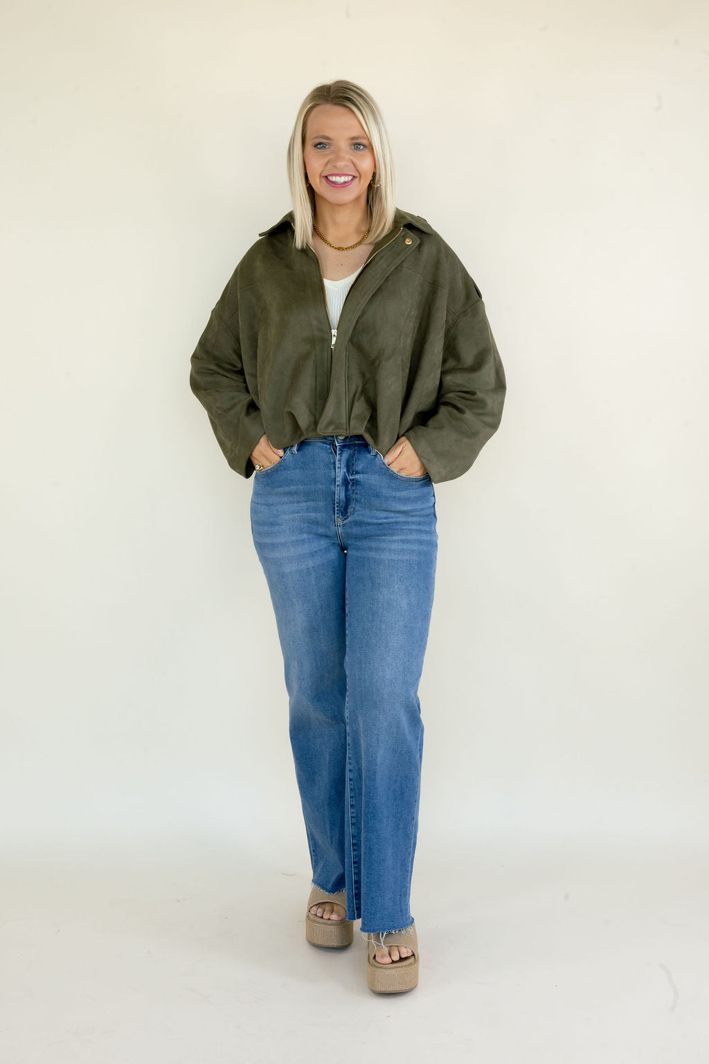 Woman modeling olive green full zip jacket with collared neckline, relaxed oversized fit, long sleeves, and blue straight leg jeans
