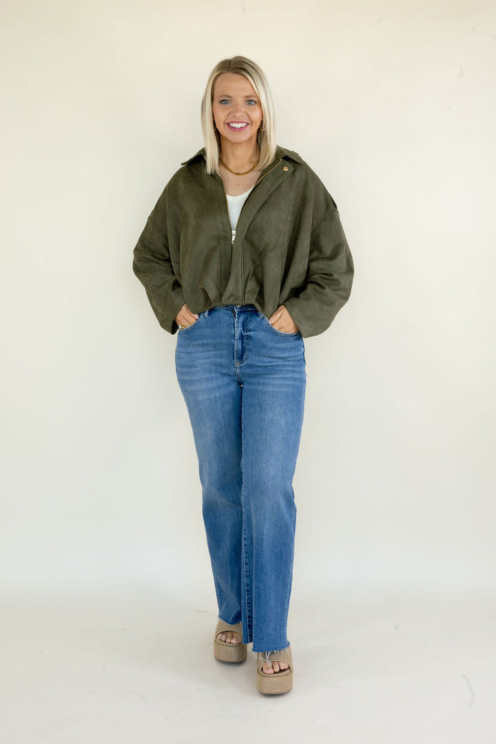 Woman modeling olive green full zip jacket with collared neckline, relaxed oversized fit, long sleeves, and blue straight leg jeans