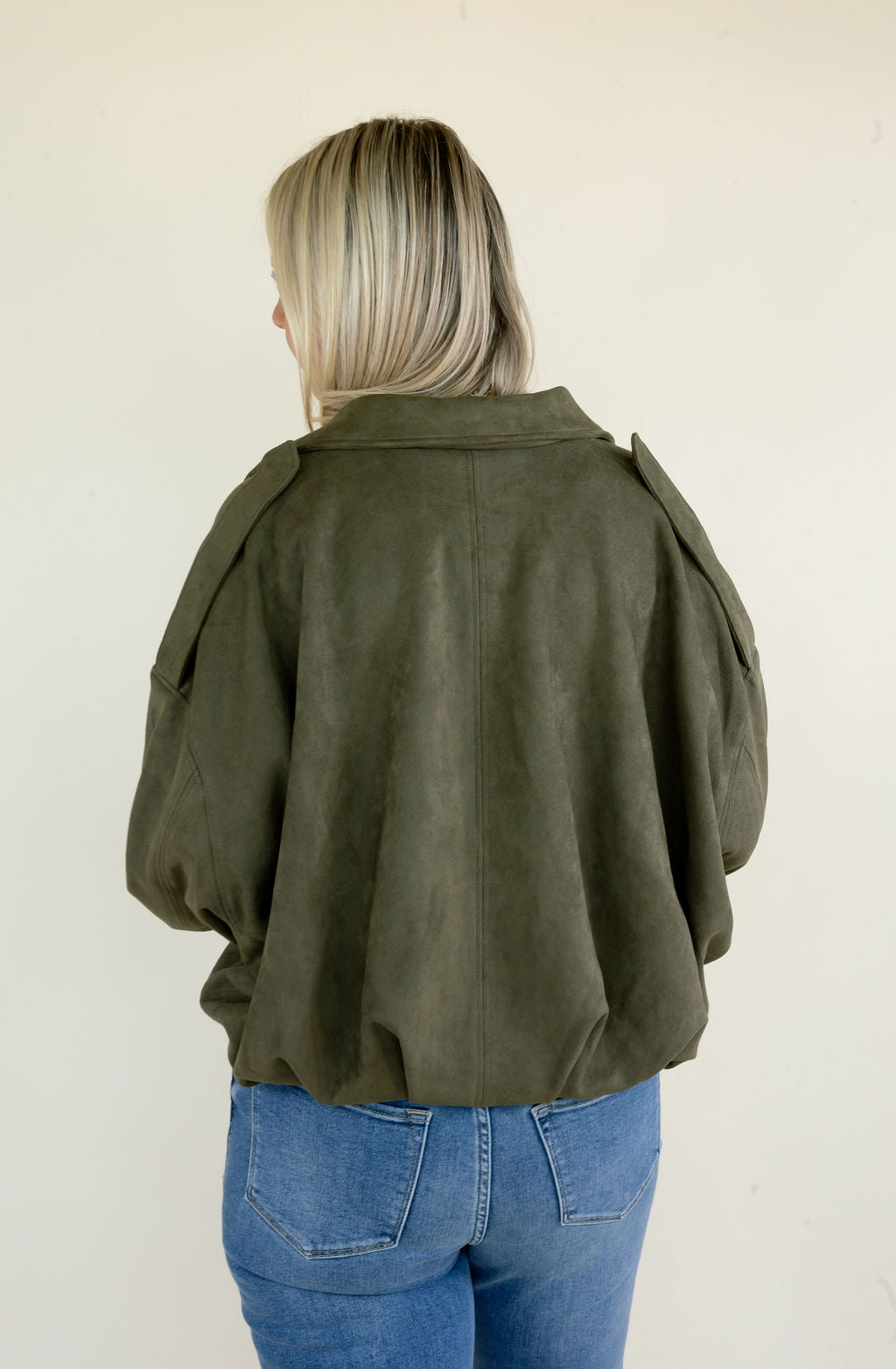 Back view of olive green full zip jacket highlighting the relaxed oversized silhouette, drop shoulders, long sleeves, and cropped hem